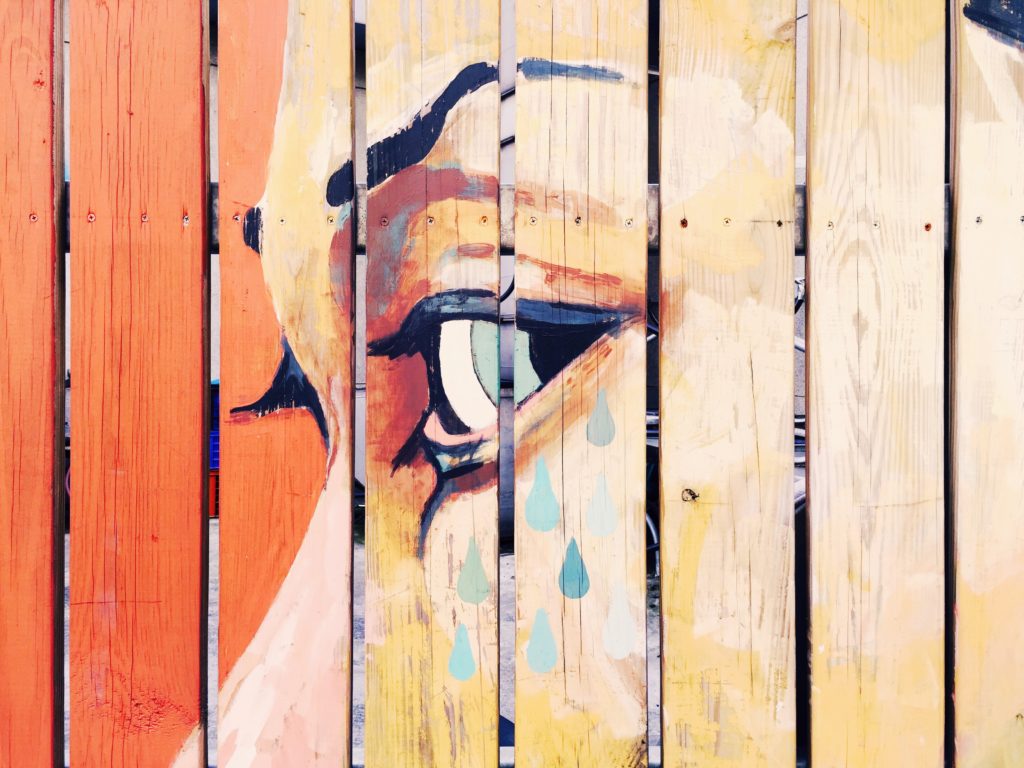 A painted fence depicting the face of a woman.