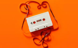 A cassette tape unravelled on an orange background.