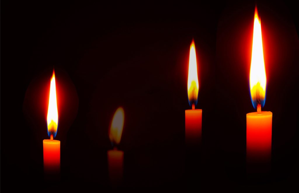 Five burning candles against a black background