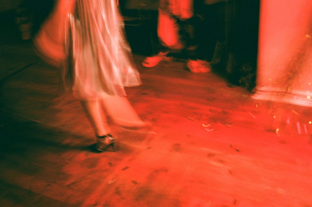Torso of female form mid-dance on a red-lit floor