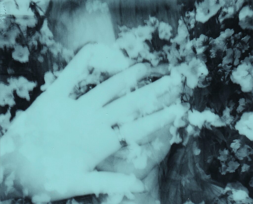 a woman covering her face with her hand; the photo is layered with flowers