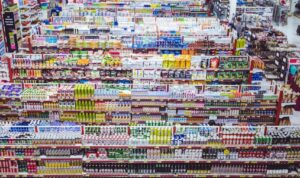 Image of several grocery store aisles and a woman appearing to be taking inventory of the items.