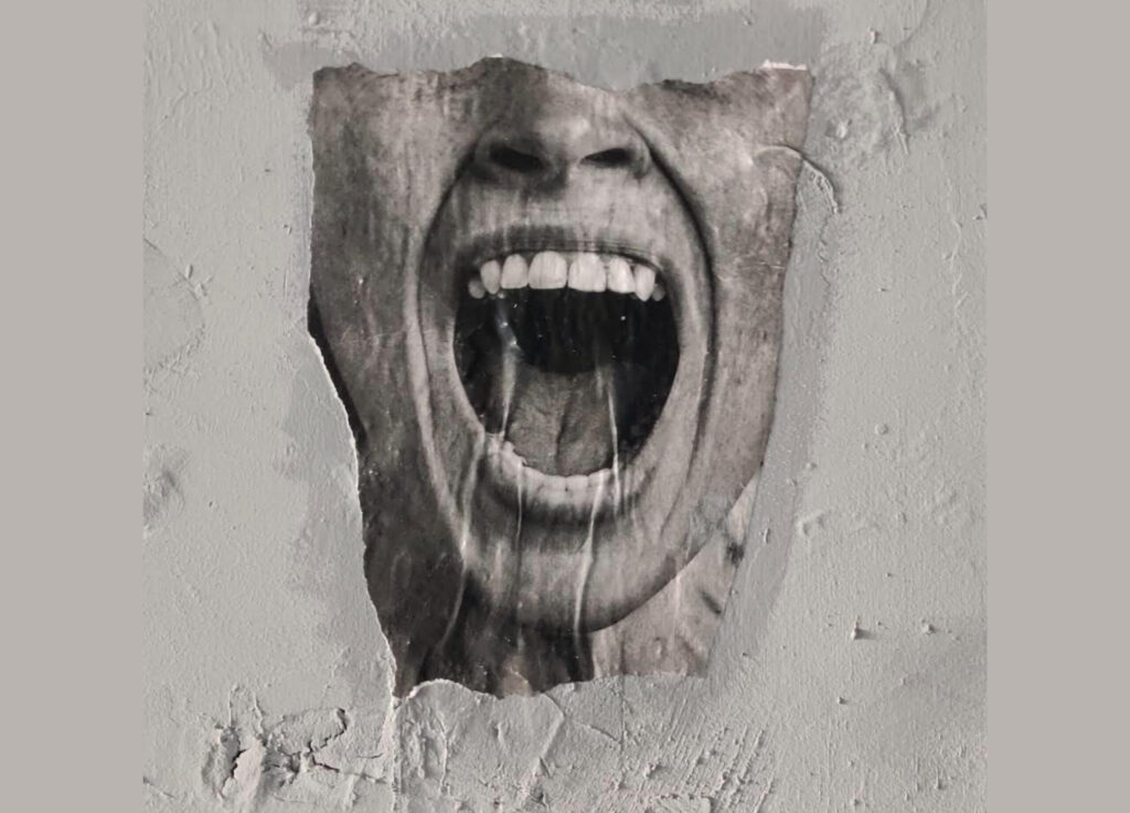 Image of a screaming face within concrete.